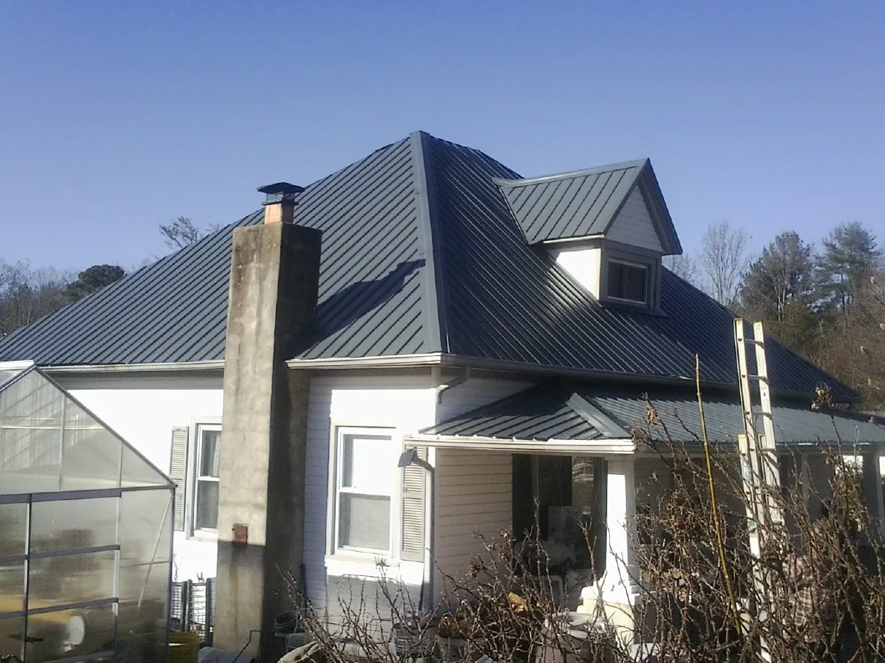 Dark blue standing seam metal roof on a white farmhouse with dormer — Slate & Tile Roof Repair by Roofing Brothers in El Monte