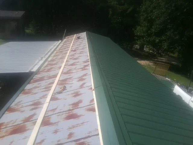 Old rusted panels beside newly installed green metal roofing — Wind Damage Roof Repair by Roofing Brothers in El Monte