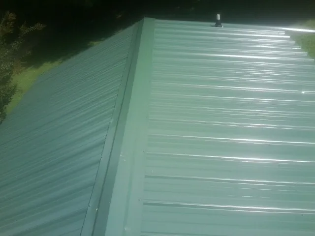 New green metal panels meeting at the ridge of a roof — Flat Roof Repair work by our crew in El Monte
