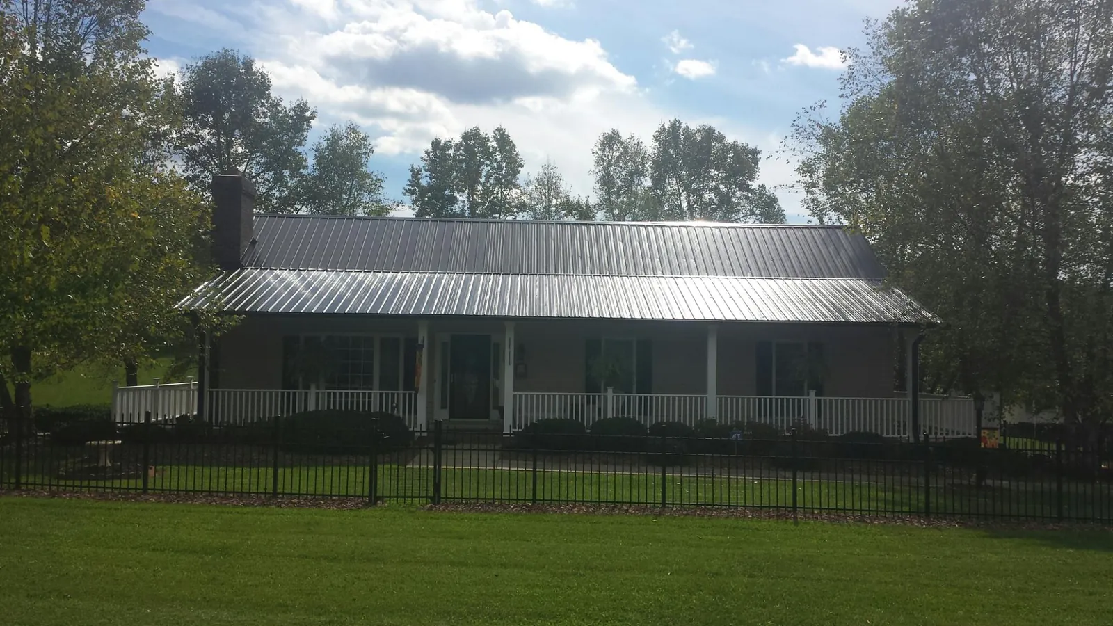 Gray metal roof on a brick ranch with a full width front porch — Gutter Guard Installation work by our crew in El Monte